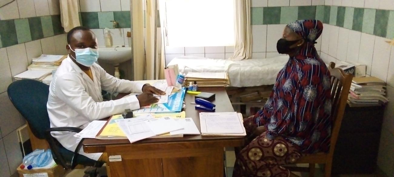 Le Dr. Euloge Houndonougbo, à gauche et en blouse, en consultation avec une patiente