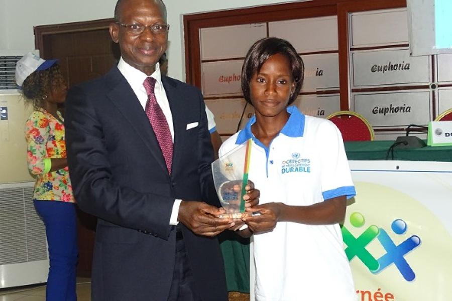 Le Représentant Résident du PNUD remettant le trophée à Laurence Ahissou.