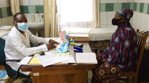 Le Dr. Euloge Houndonougbo, à gauche et en blouse, en consultation avec une patiente